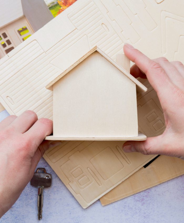 close-up-hand-holding-wooden-miniature-house-model